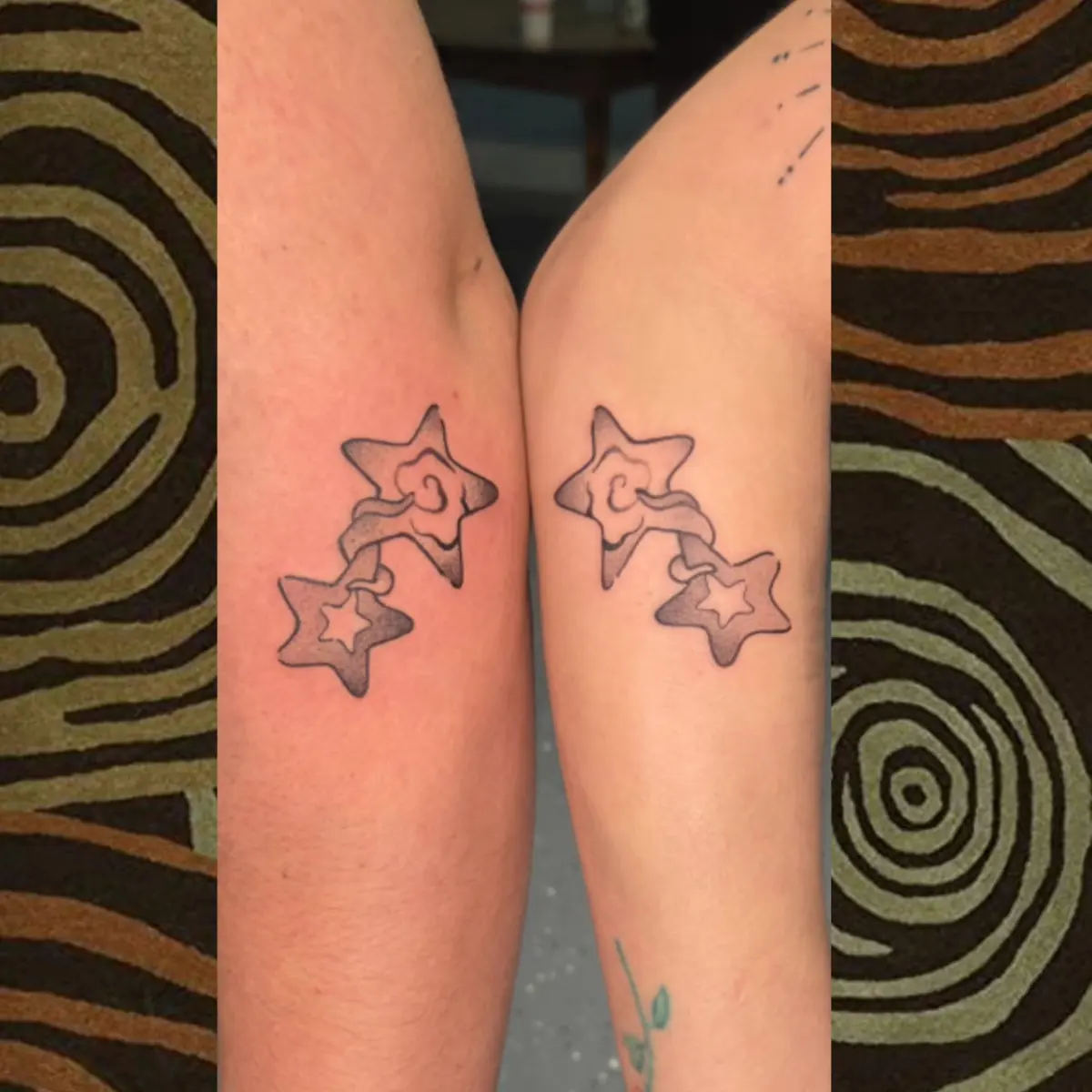Matching outlined star tattoos on two arms held side by side