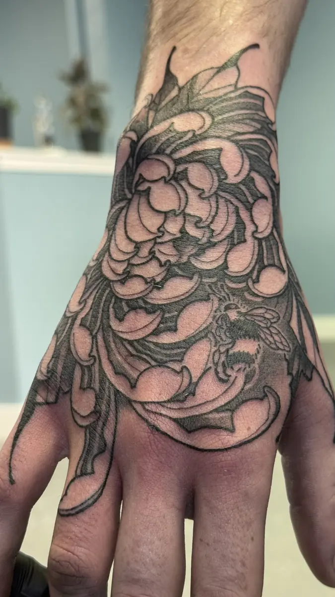 Blackwork chrysanthemum hand tattoo with bold outlines and heavy shading, tattooed at Blind Fox Tattoo in Amarillo, TX