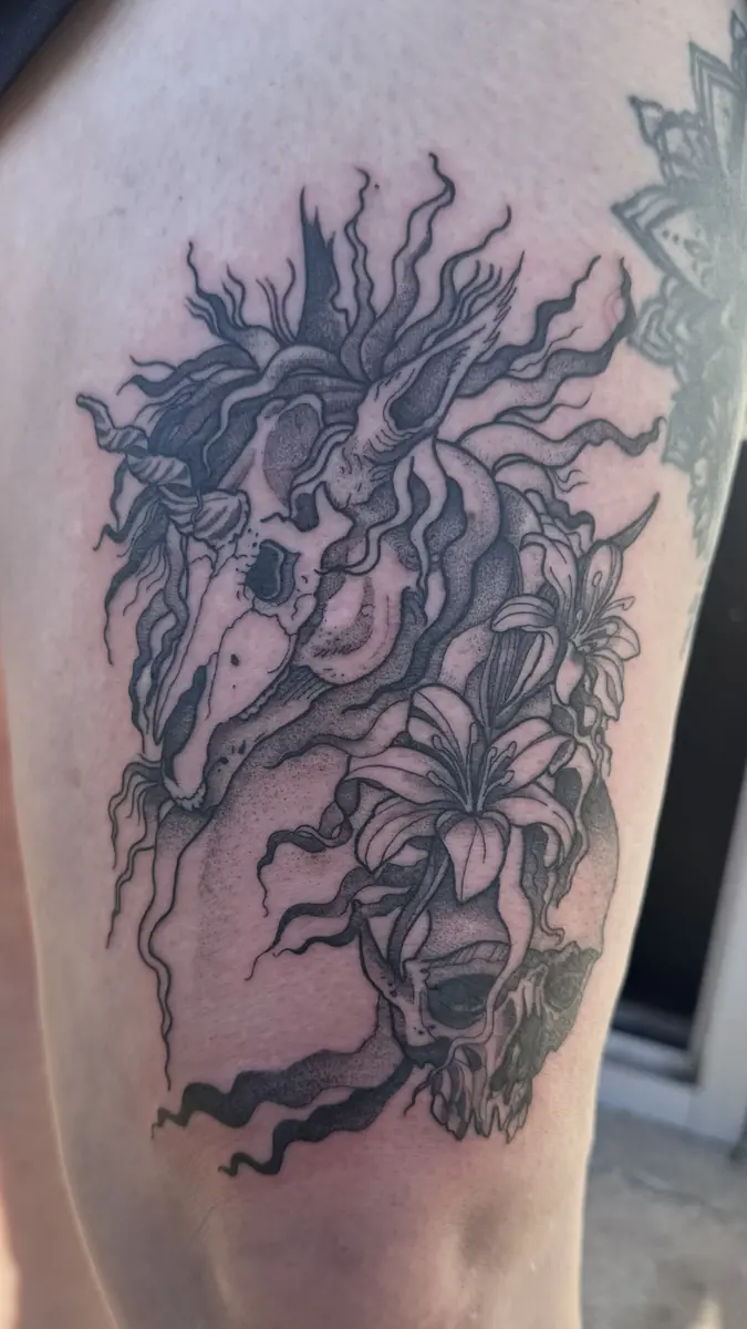Black and grey blackwork tattoo of a horse with lilies on a thigh
