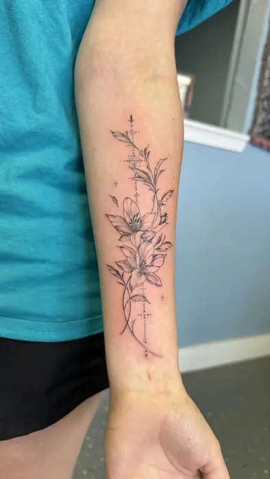 Fine line botanical tattoo trailing down a forearm to the wrist