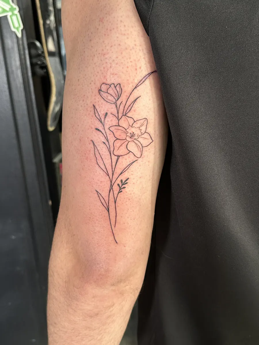 Fine line floral tattoo with single-needle linework on an upper arm