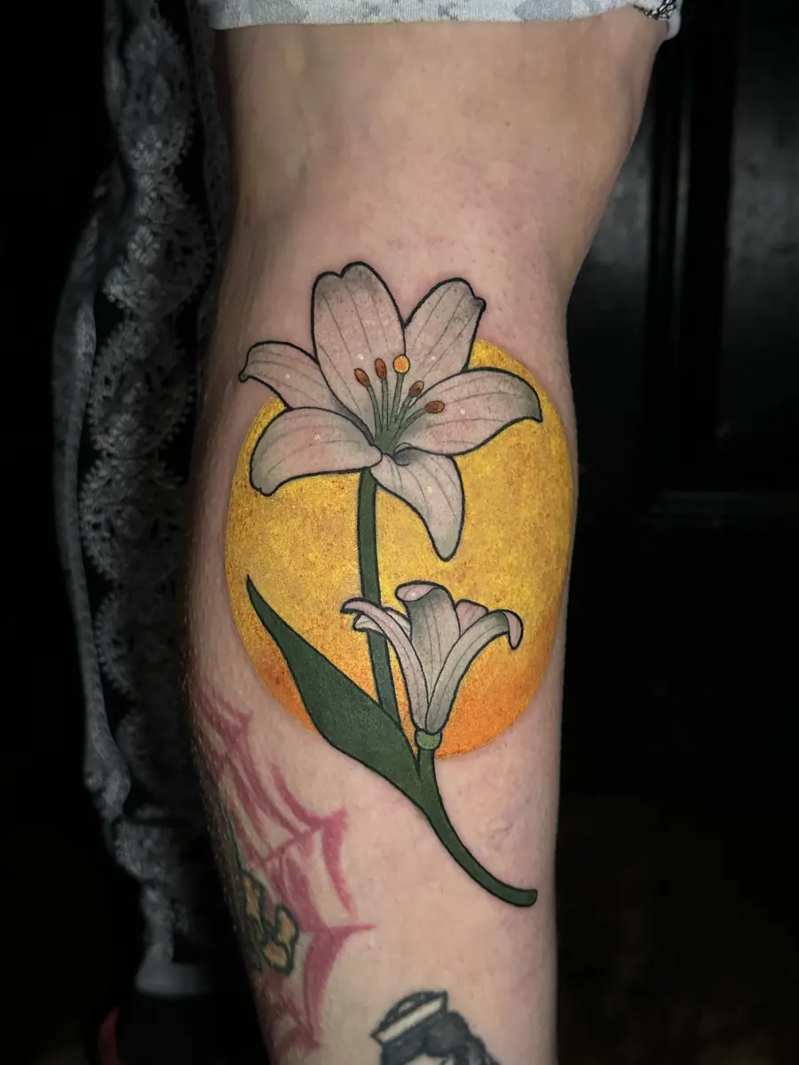 Neo-traditional white lily tattoo over a yellow halo on a calf, covering older work