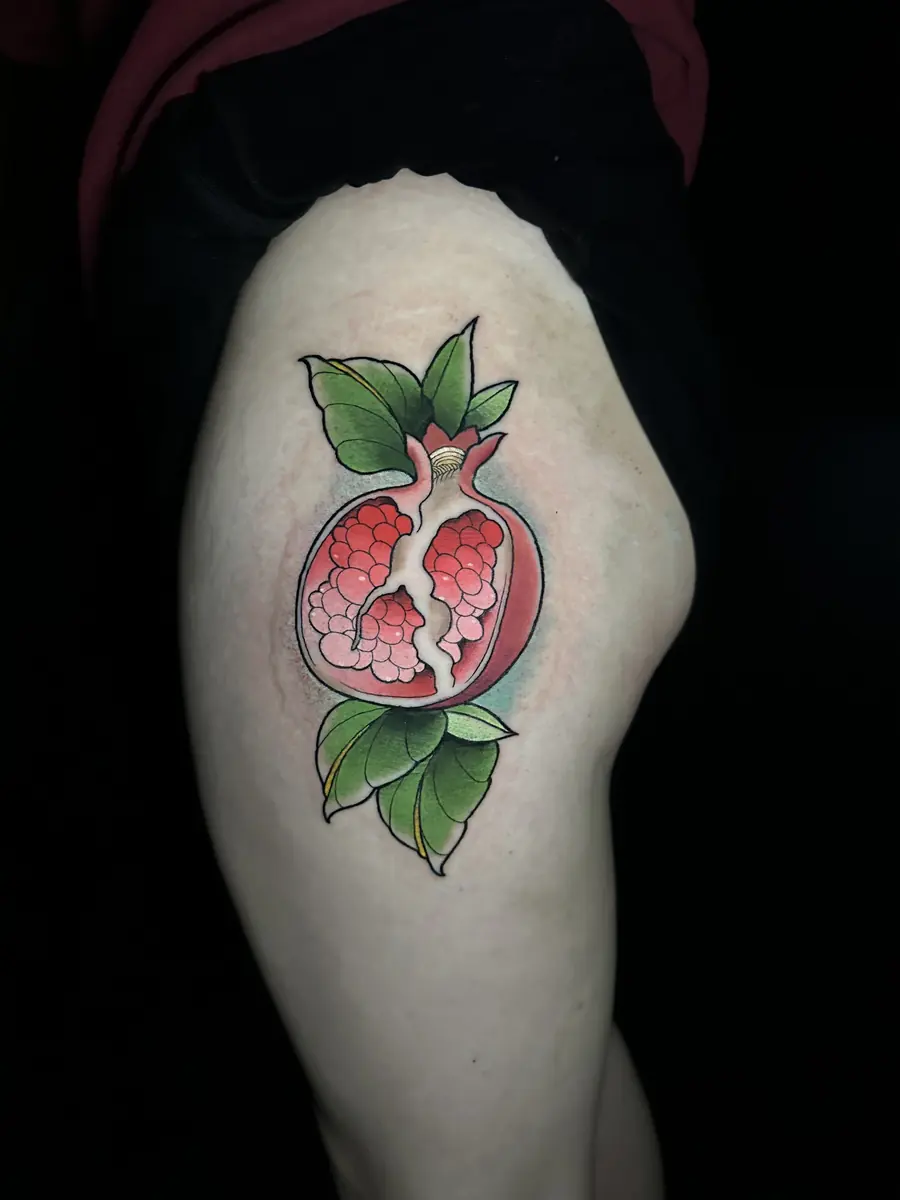 Neo-traditional pomegranate tattoo in full color on a shoulder