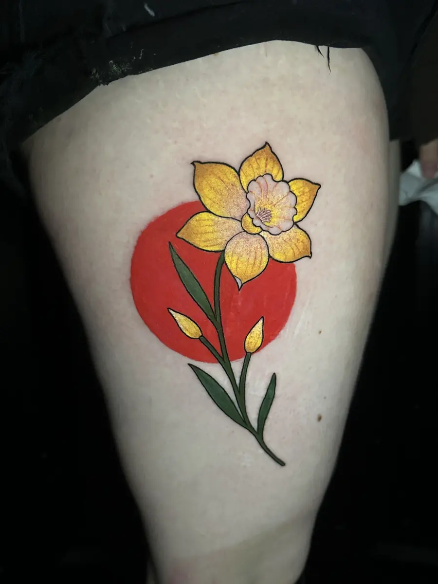 Traditional daffodil tattoo set over a solid red circle on a thigh