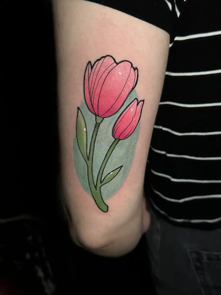 Traditional pink tulip tattoo with bold outlines on an upper arm
