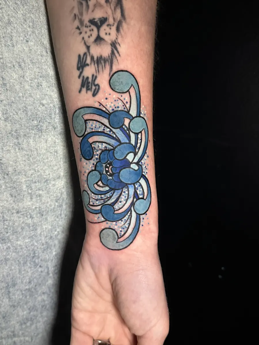 Watercolor style blue flower tattoo with flowing petals on a forearm